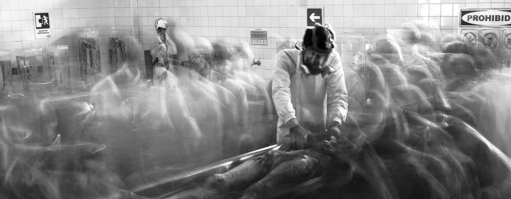 Man working in the university teaching morgue in Medellin, Columbia, surrounded by ghostly images of other students