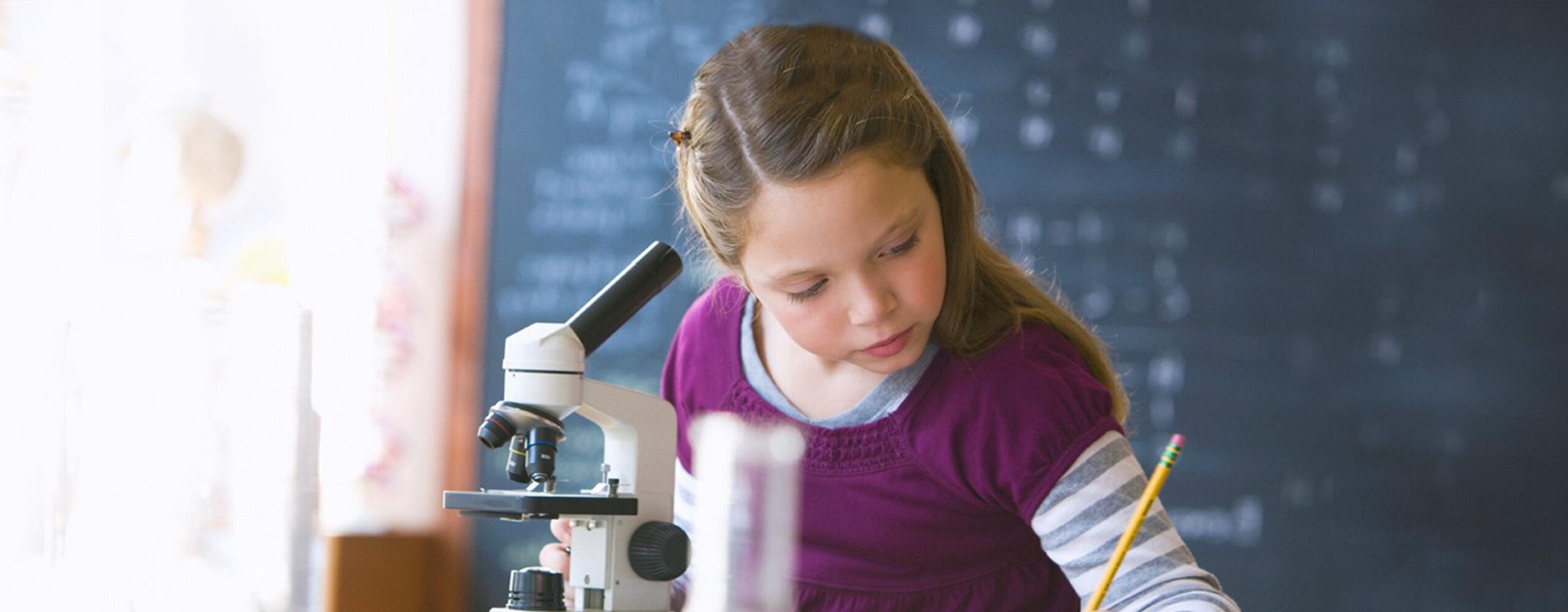 Girl looking into classroom microscope (Image © Blend Images - KidStock/Getty Images)