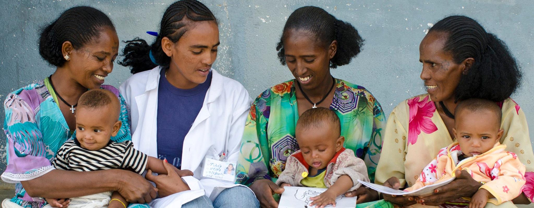 Three mothers and their babies sitting on a step with a health worker in Ethiopia. The babies have just been weighed to monitor their growth.