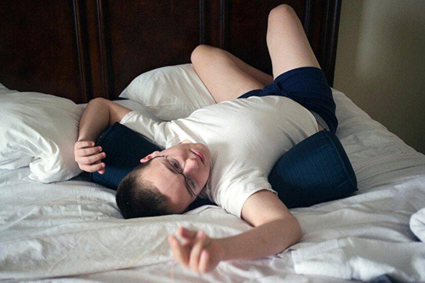 A 19-year-old man who is on the autistic spectrum lying on a bed playing with a piece of string