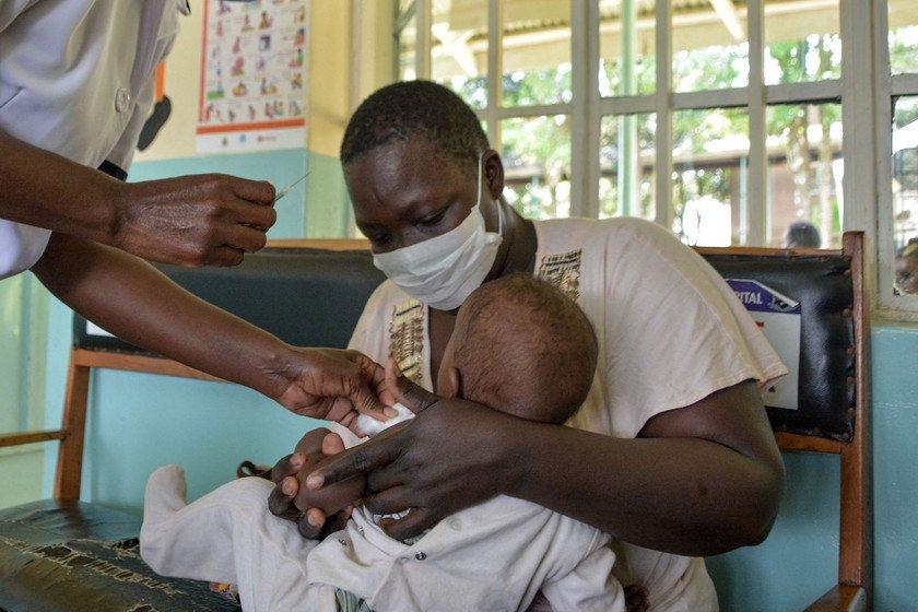 A child gets a malaria vaccination in a hospital. They are being held by their parent.