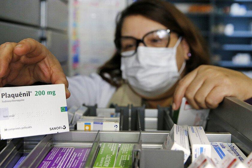  A pharmacy employee wearing a protective mask shows a box of Plaquenil (Chloroquine). 