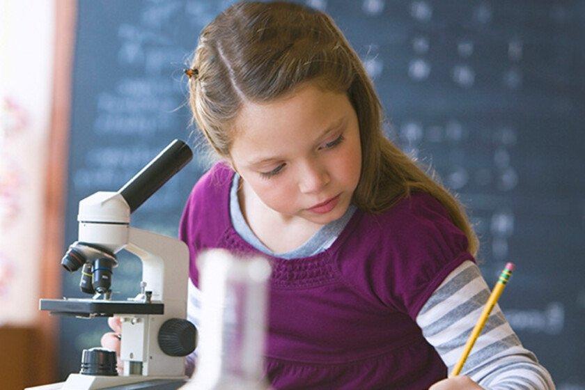 Girl looking into classroom microscope (Image © Blend Images - KidStock/Getty Images)