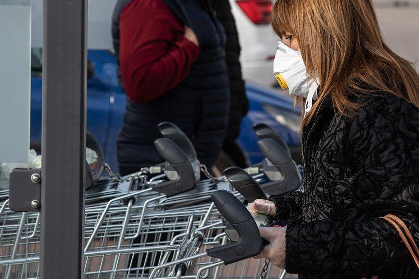 Woman wears face mask and pushes shopping trolley