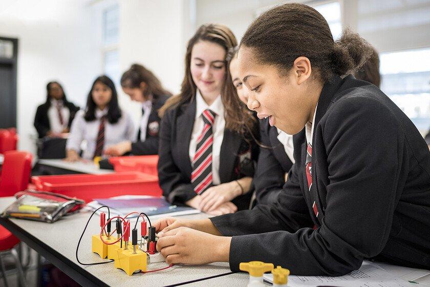 Three female students carry out science experiment involving an electric circuit