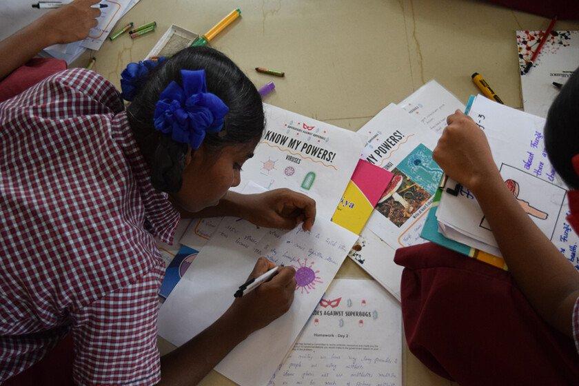 Indian schoolchildren creating comics with paper and pens.
