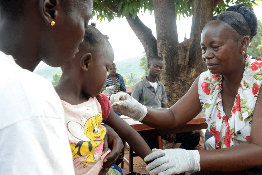A girl gets a vaccination against measles from a health worker 