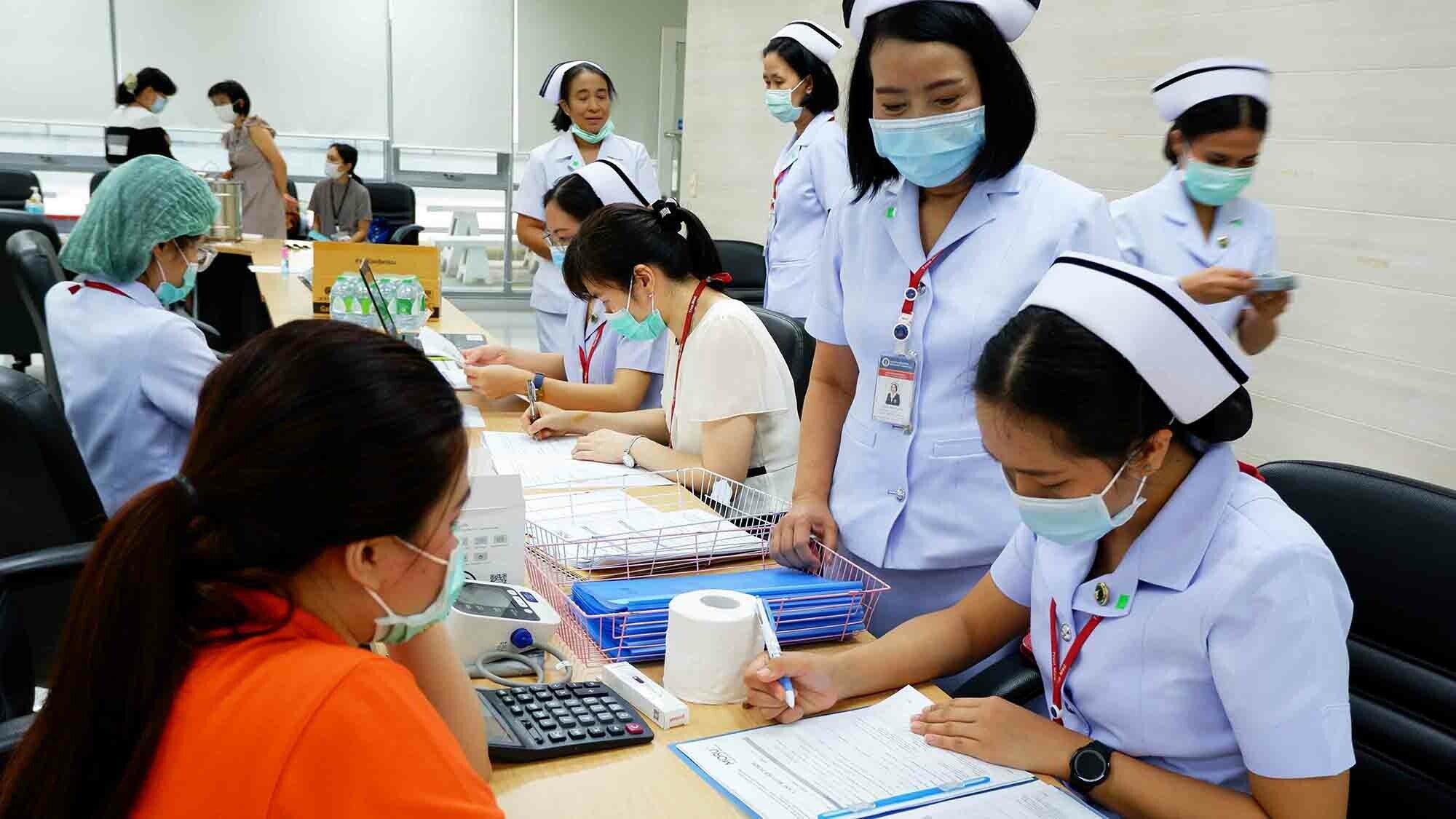 Two nurses take down details of a patient as part of the COPCOV trial in Thailand.