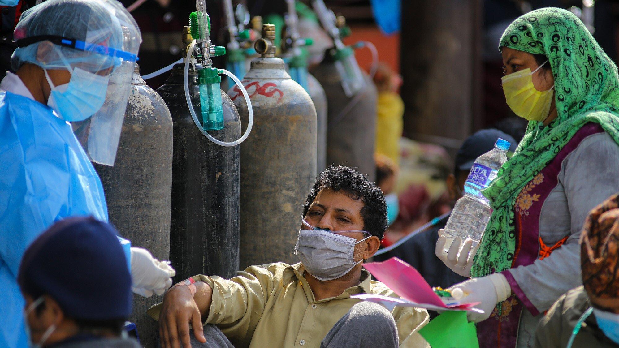 A doctor checks a Covid-19 patient while receiving oxygen outside a hospital in Nepal
