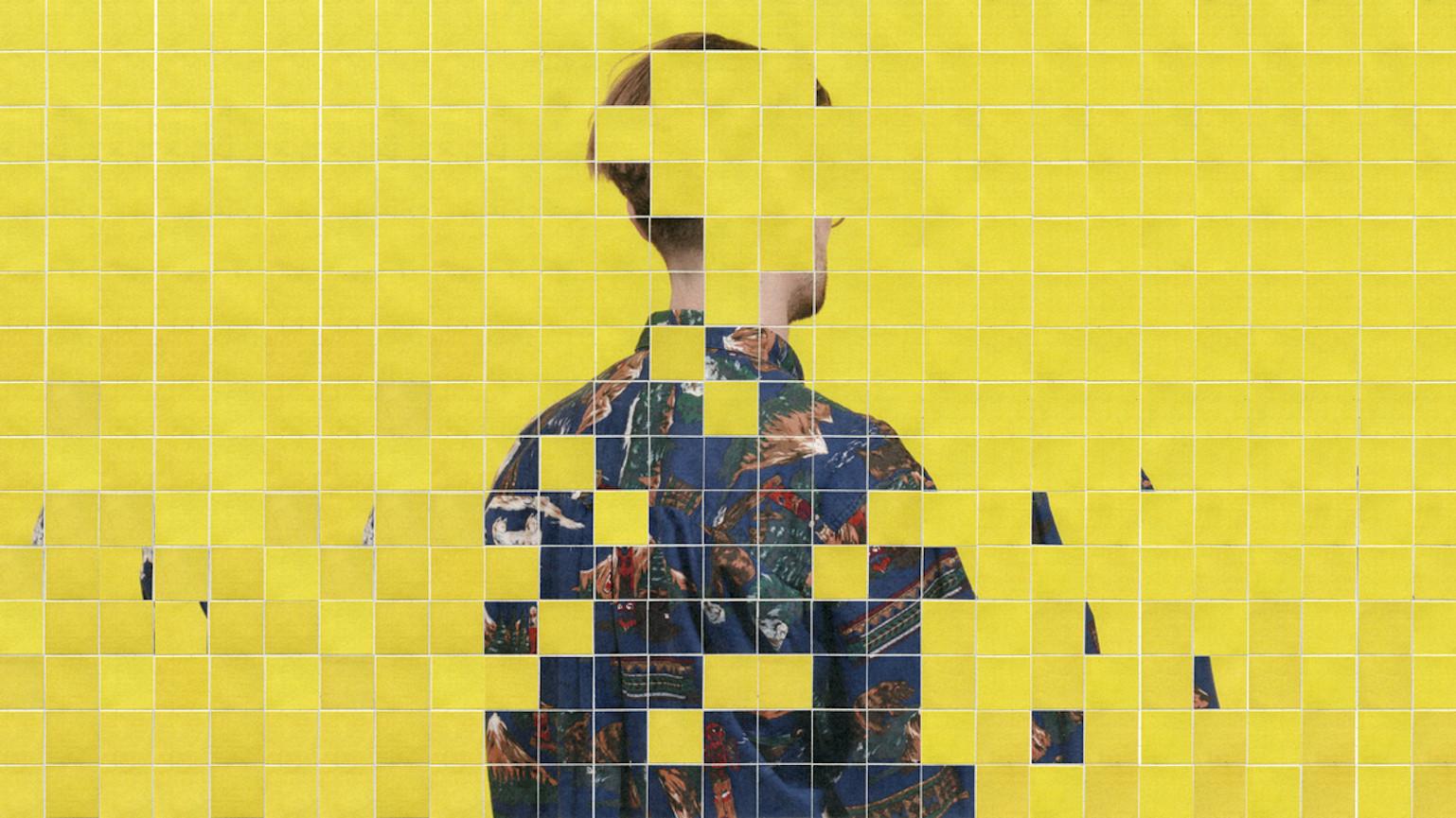 A wall with yellow tiles. Some of the tiles are missing revealing an image of a man facing away.