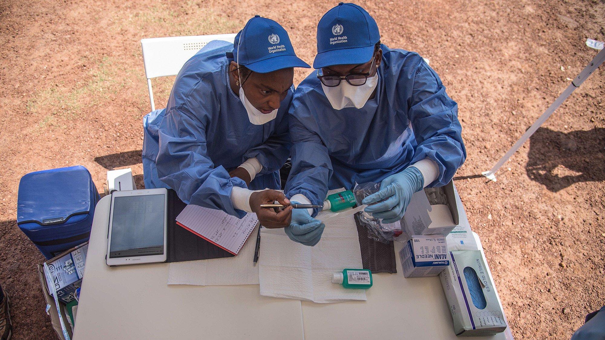 Two nurses prepare to administer vaccines. 